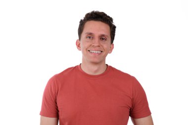 Genç bir adam, mutlu ve gülümsüyor, kırmızı tişört giyiyor, beyaz bir arka planda izole edilmiş.