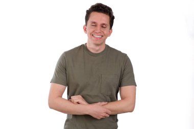 Genç adam, sakin ve mutlu, yeşil tişört giyiyor, beyaz bir arka planda izole edilmiş.