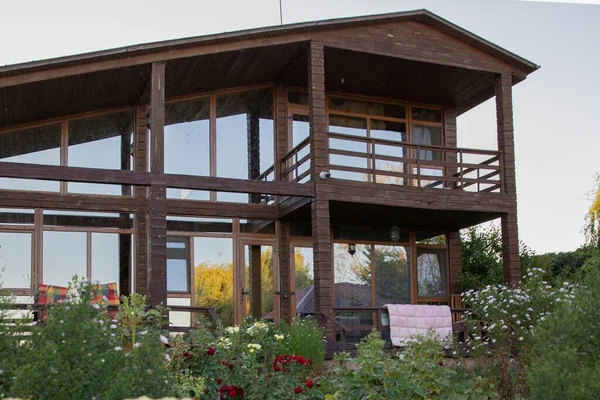 İki katlı modern ahşap ev yeşil bahçe ve bitki konseptiyle çevrili büyük panoramik pencereli kırsal yaşam tarzı ve sürdürülebilir mimari