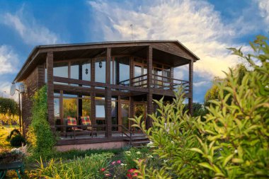 İki katlı modern ahşap ev yeşil bahçe ve bitki konseptiyle çevrili büyük panoramik pencereli kırsal yaşam tarzı ve sürdürülebilir mimari