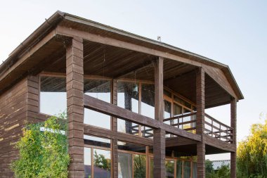 İki katlı modern ahşap ev yeşil bahçe ve bitki konseptiyle çevrili büyük panoramik pencereli kırsal yaşam tarzı ve sürdürülebilir mimari