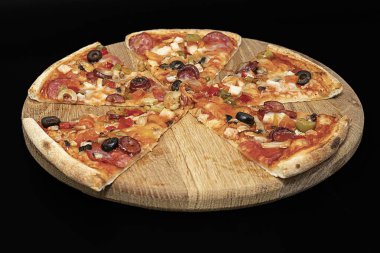 Salamlı, peynirli, eritilmiş zeytinli ve sebzeli pizza. Siyah arka planda servis panosunda dilimlenmiş.