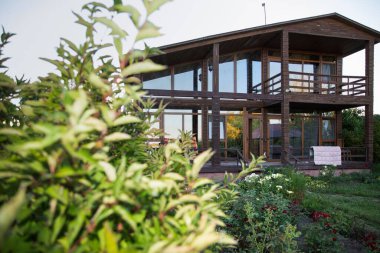 Çevresi yeşil bahçe ve çiçeklerle çevrili iki katlı modern ahşap ev rahat kırsal bir ortam yaratıyor.