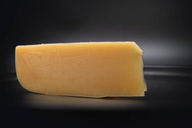 Siyah arka plana peynir kaması yerleştirilmiş. Yakın plan. Süt ürünleri, sağlıklı beslenme, yemek malzemeleri ve gurme ürünleri kavramı.