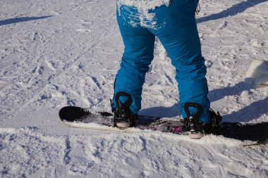 Kışın karlı bir yamaçta kar kayağı yapan mavi pantolonlu bir snowboardcu. Kış sporu, aktif yaşam tarzı ve açık hava eğlencesi..