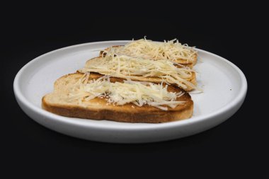 Beyaz tabakta rendelenmiş peynirle kaplı kızarmış ekmek dilimleri. Basit ev yapımı aperatif ya da aperatif, kahvaltı, yemek pişirme, yemek tarifleri ve menü tasarımı için ideal..