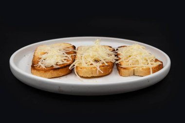 Beyaz tabakta rendelenmiş peynirle kaplı kızarmış ekmek dilimleri. Basit ev yapımı aperatif ya da aperatif, kahvaltı, yemek pişirme, yemek tarifleri ve menü tasarımı için ideal..