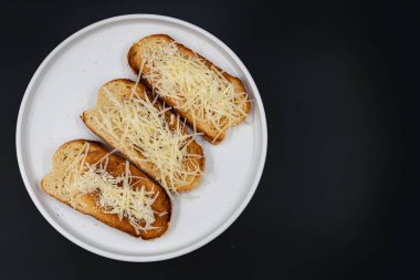 Beyaz tabakta rendelenmiş peynirle kaplı kızarmış ekmek dilimleri. Basit ev yapımı aperatif ya da aperatif, kahvaltı, yemek pişirme, yemek tarifleri ve menü tasarımı için ideal..