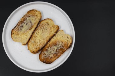 Beyaz tabakta rendelenmiş peynirle kaplı kızarmış ekmek dilimleri. Basit ev yapımı aperatif ya da aperatif, kahvaltı, yemek pişirme, yemek tarifleri ve menü tasarımı için ideal..