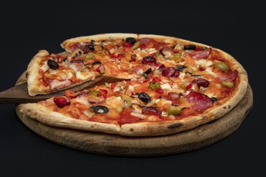 Tahta tahtada servis edilen peynirli, zeytinli, mantarlı, domatesli ve sebzeli nefis ev yapımı pizza menü, kafe ve reklam için yakın plan yiyecek konsepti.