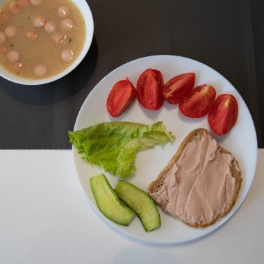 Ekmek ve yayılmış dengeli yemek, taze salatalık, marul, dilimlenmiş domates ve bir kase çorba. Kahvaltı, öğle yemeği veya diyet menüsü için sağlıklı gıda kavramı