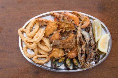 Metal bir tabakta servis edilen kızarmış deniz ürünleri çeşitlerini yakın çekim yapın. Kalamar halkaları, balık, karides ve midye. Geleneksel Akdeniz mutfağı, gurme yemekleri ve restoran yemekleri.