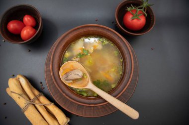 Et ve sebzeli ev yapımı çorbanın en üst görüntüsü ekmek çubukları ve taze domateslerle servis edilen köy kil kasesinde. Geleneksel sıcak yemek ve sağlıklı yiyecek konsepti