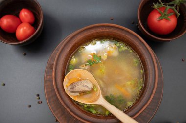 Et ve sebzeli ev yapımı çorbanın en üst görüntüsü ekmek çubukları ve taze domateslerle servis edilen köy kil kasesinde. Geleneksel sıcak yemek ve sağlıklı yiyecek konsepti