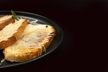 Eritilmiş peynir dilimli, siyah tabakta kızartılmış altın ekmek. Ev yapımı kahvaltı, fast food, konforlu yemek ve yemek tarifi..