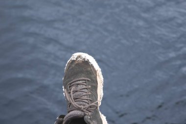 Tabanında kar olan bir kış botunun kapağı su yüzeyinde asılıdır. Soğuk hava, açık hava yaşam tarzı ve mevsimsel macera kavramı.