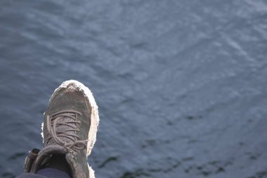 Tabanında kar olan bir kış botunun kapağı su yüzeyinde asılıdır. Soğuk hava, açık hava yaşam tarzı ve mevsimsel macera kavramı.