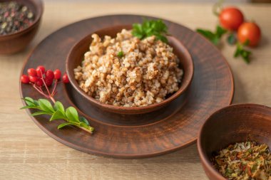 Maydanoz ve biberli kil kasede servis edilen pişmiş karabuğday lapası, geleneksel sağlıklı yiyecek ve vejetaryen diyet konsepti..