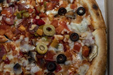 Zeytin, salam, mantar, peynir ve sebzeli taze pişmiş pizza yakın çekim. İtalyan mutfağı, fast food ve restoran menüsü konsepti.