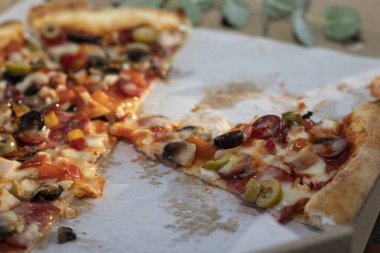 Peynirli, salamlı, zeytinli ve sebzeli dilimlenmiş pizzayı karton teslimat kutusuna koy. Fast food, paket yemek ve pizza teslimatı..