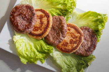 Assorted fried meat and fish patties on fresh lettuce leaves. Homemade food, healthy meal, and traditional cuisine concept.