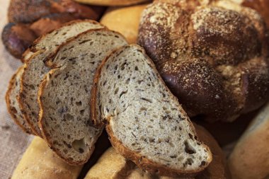 Türlü taze ekmek somunlarını ve kırsal dokulu dilimleri kapatın. Ev yapımı fırın, geleneksel yemekler, zanaatkar pişirme ve organik ekmek konsepti..