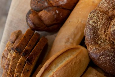 Köy arka planında çeşitli taze ekmek somunları ve ekmekleri kapatın. Geleneksel ev yapımı fırın çeşitleri, zanaatkar yemekleri ve organik ekmek kavramı.