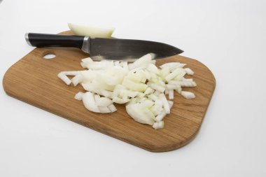 Taze beyaz soğan, mutfak bıçağıyla ahşap bir kesme tahtasının üzerinde ince ince doğranmış. Yemek malzemesi, ev yapımı yemek hazırlama ve aşçılık geçmişi kavramı.