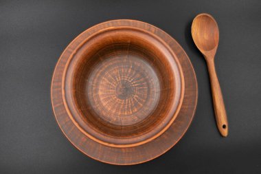 Kırsal ahşap kase ve kaşık siyah arka plana yerleştirilmiş. Geleneksel mutfak gereçleri, çevre dostu doğal gereçler, köy tarzı aşçılık konsepti..