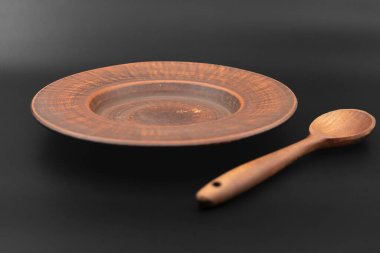 Kırsal ahşap kase ve kaşık siyah arka plana yerleştirilmiş. Geleneksel mutfak gereçleri, çevre dostu doğal gereçler, köy tarzı aşçılık konsepti..