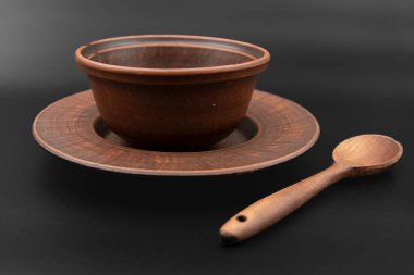 Kırsal ahşap kase ve kaşık siyah arka plana yerleştirilmiş. Geleneksel mutfak gereçleri, çevre dostu doğal gereçler, köy tarzı aşçılık konsepti..