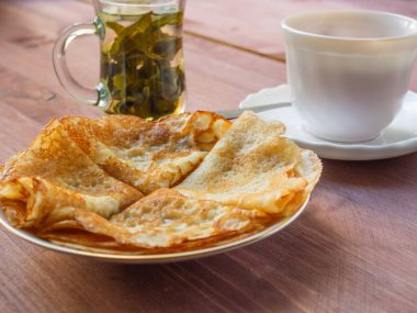 Ahşap bir masa üzerinde yeşil Çince çay ile bir fincan tabak krep,