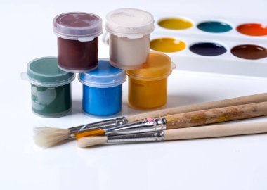 Kavanoz, fırçalar ve suluboya beyaz zemin üzerine guaş