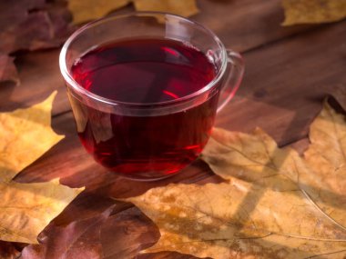 Güneş ışığı tarafından yaktı, siyah ahşap bir masa üzerinde arka planda fincan çay ve akçaağaç yaprakları