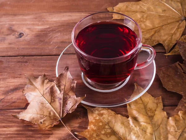 Red tea and dry leaves on a wooden background