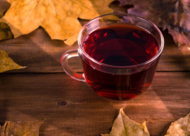 Sonbahar tarafından çevrili bir ahşap masa üzerinde sıcak çay yaprakları