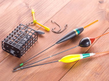 Balık tutma araçları, yüzen, kanca ve ahşap arka plan üzerinde siyah bir metal besleyici