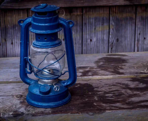 Blue kerosene lamp on a wooden background in the rain
