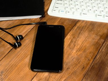 Klavye, kulaklık ile smartphone ve ahşap bir masa üzerinde bir günlük.