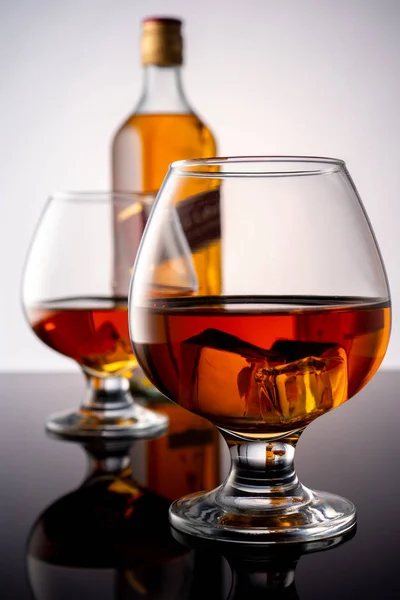 Glass of whiskey on ice with a bottle on a dark background — Stock Photo, Image