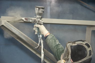 Bir adam toz boya metal ürünleri üretir.