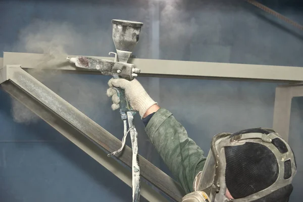 Bir adam toz boya metal ürünleri üretir.