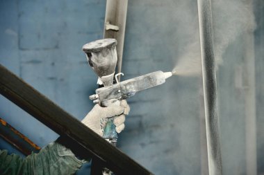 Bir adam toz boya metal ürünleri üretir.