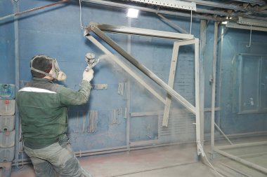 Bir adam toz boya metal ürünleri üretir.