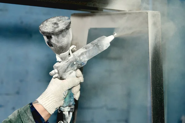 Bir adam toz boya metal ürünleri üretir.