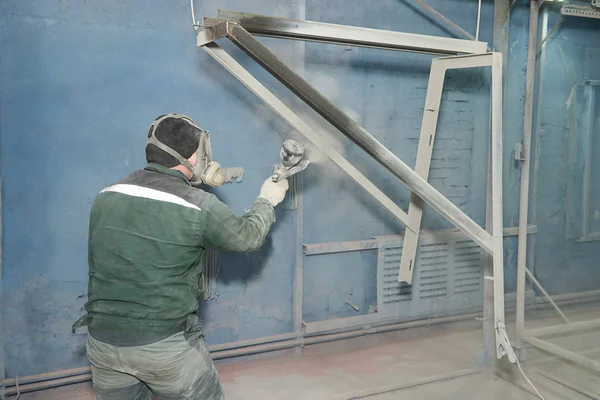 Bir adam toz boya metal ürünleri üretir.