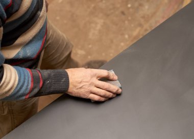 bir adam zımpara ile bir sünger ile siyah mat yüzey davranır.