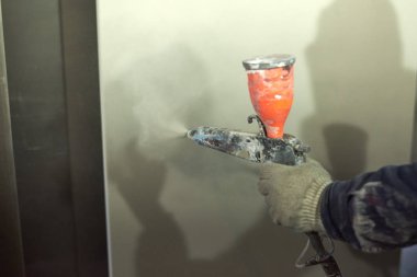 Bir adam toz boya metal ürünleri üretir.