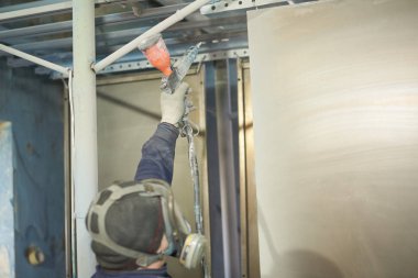 Bir adam toz boya metal ürünleri üretir.