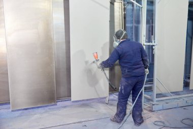 Bir adam toz boya metal ürünleri üretir.